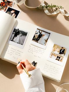 a person holding a pen and writing on an open book with photos attached to it