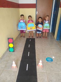 three children holding up signs in front of a traffic light on the floor next to a road