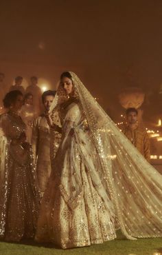 the bride and groom are standing in front of their wedding party at night, dressed in gold sequins