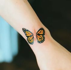 a small butterfly tattoo on the wrist of a woman's hand, with one wing spread out