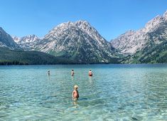 several people are wading in the water near mountains