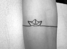 a black and white photo of a person's arm with a paper boat on it