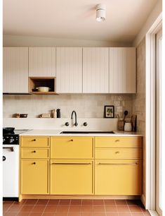 a kitchen with yellow cabinets and white appliances