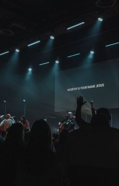 a group of people standing on top of a stage with their hands up in the air