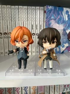 two anime figurines sitting on top of a shelf