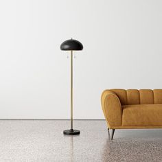 an orange couch and black floor lamp in a room with white walls, concrete flooring and shiny floors