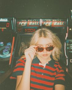 a woman wearing sunglasses standing in front of a slot machine with her hand on her face