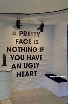 a white toilet sitting in a bathroom next to a black and white sign that says a pretty face is nothing if you have an ugly heart