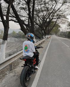 a man riding on the back of a motorcycle down a road