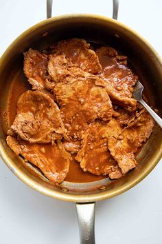 a pot filled with meat and sauce on top of a table