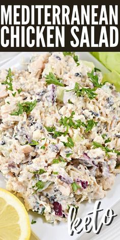 a white plate topped with chicken salad next to lemon wedges