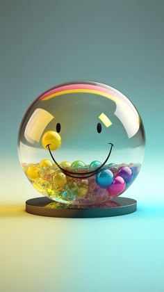 a glass ball with a smiley face and colorful balls in it's mouth, sitting on top of a table