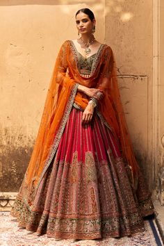 a woman in an orange and red lehenga