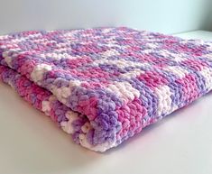 a crocheted blanket sitting on top of a white table next to a window