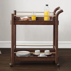 a wooden serving cart with plates and drinks on it