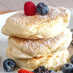 a stack of pancakes with powdered sugar and berries on top