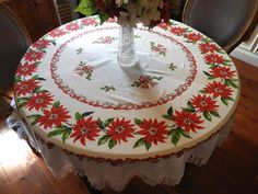 a white table with red poinsettias on it and a vase filled with flowers