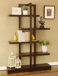 a book shelf with books, vases and pictures on the wall behind it in a living room