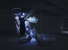 a woman with wings sitting on the ground in front of a garage door at night