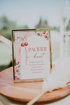 a wooden table topped with a sign next to a white fluffy ball and some feathers