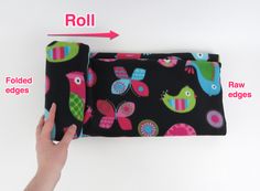 a hand holding a black and pink pouch with colorful birds on it, labeled roll