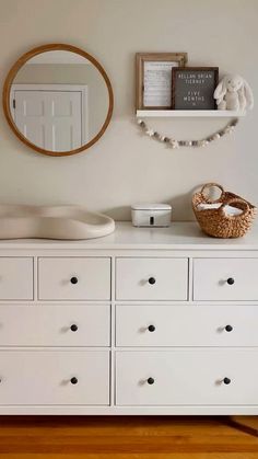 a white dresser with drawers and a mirror on the wall above it is a baby's crib