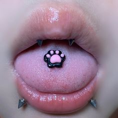 a close up of a person's tongue with pink and black spikes on it