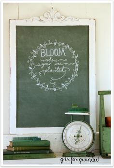 a chalkboard with the words bloom written on it next to books and a clock