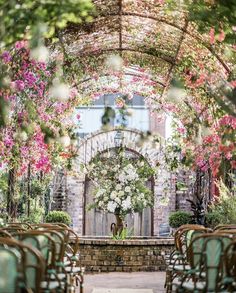 an outdoor ceremony set up with chairs and flowers on the arch over looking the garden