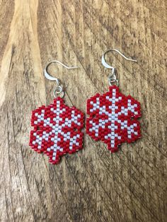 red and white cross stitched earrings on wooden table