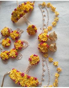 several necklaces with flowers and pearls are on the table next to some other beads