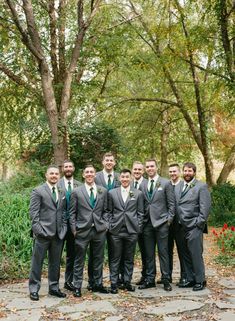 a group of men standing next to each other in front of trees and leaves on the ground