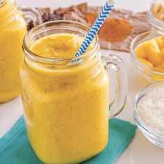 two mason jars filled with yellow smoothie next to bowls of macaroni and cheese