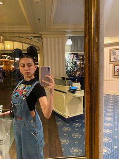 a woman taking a selfie in front of a mirror with mickey mouse ears on her head