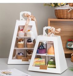 two white boxes with cupcakes in them on a table next to each other