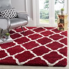 a living room with a chair, rug and window in the background that has a large red area rug on top of it