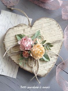 a heart shaped box with flowers on top of it next to some paper and twine