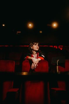 a woman sitting in a red chair with her arms crossed