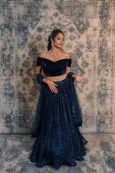 Spice up your style statement with this navy blue coloured lehenga No matter if you want to be a showstopper at any wedding or small ceremony, then this blue coloured lehenga is apt for you. This lehenga is decorated with sequined work and comes along with an off-shoulder velvet blouse. This lehenga is easy to carry so that you can dance around with ease and feel relaxed throughout the ceremony. Due to its appealing design, this lehenga will prove to be a great choice for you without burning a h Navy Blue Velvet Lehenga, Bride Lehenga Designs, Henna Night Outfit, Navy Blue Velvet Blouse, Blue Sequin Lehenga, Lehenga Blouse Styles, Dark Blue Lehenga, Velvet Skirt Outfit