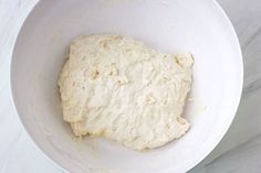 a white bowl filled with dough on top of a counter