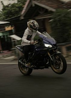 a man riding on the back of a motorcycle down a street