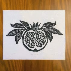 a piece of paper with a pomegranate on it sitting on top of a wooden table