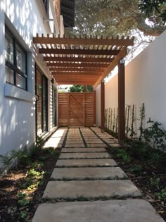 an outdoor walkway leading to a house with wood slatted doors and wooden trelliss