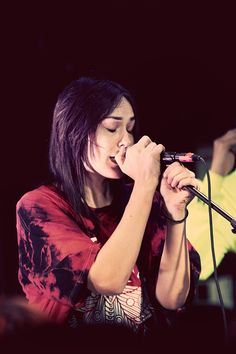 a woman singing into a microphone on stage