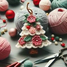 a crocheted christmas tree ornament surrounded by balls of yarn and knitting needles