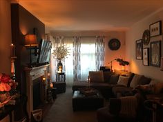 a living room filled with furniture and a fire place next to a window covered in curtains