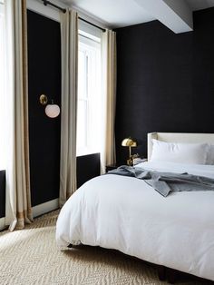 a bedroom with black walls and white bedding