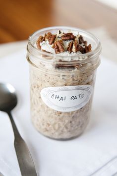 a jar filled with oatmeal sitting on top of a white napkin next to a spoon