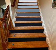 the stairs are painted black and white with blue strips on them, along with wood handrails