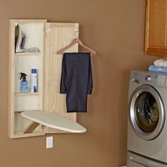 an ironing board is hanging on the wall next to a washer and dryer